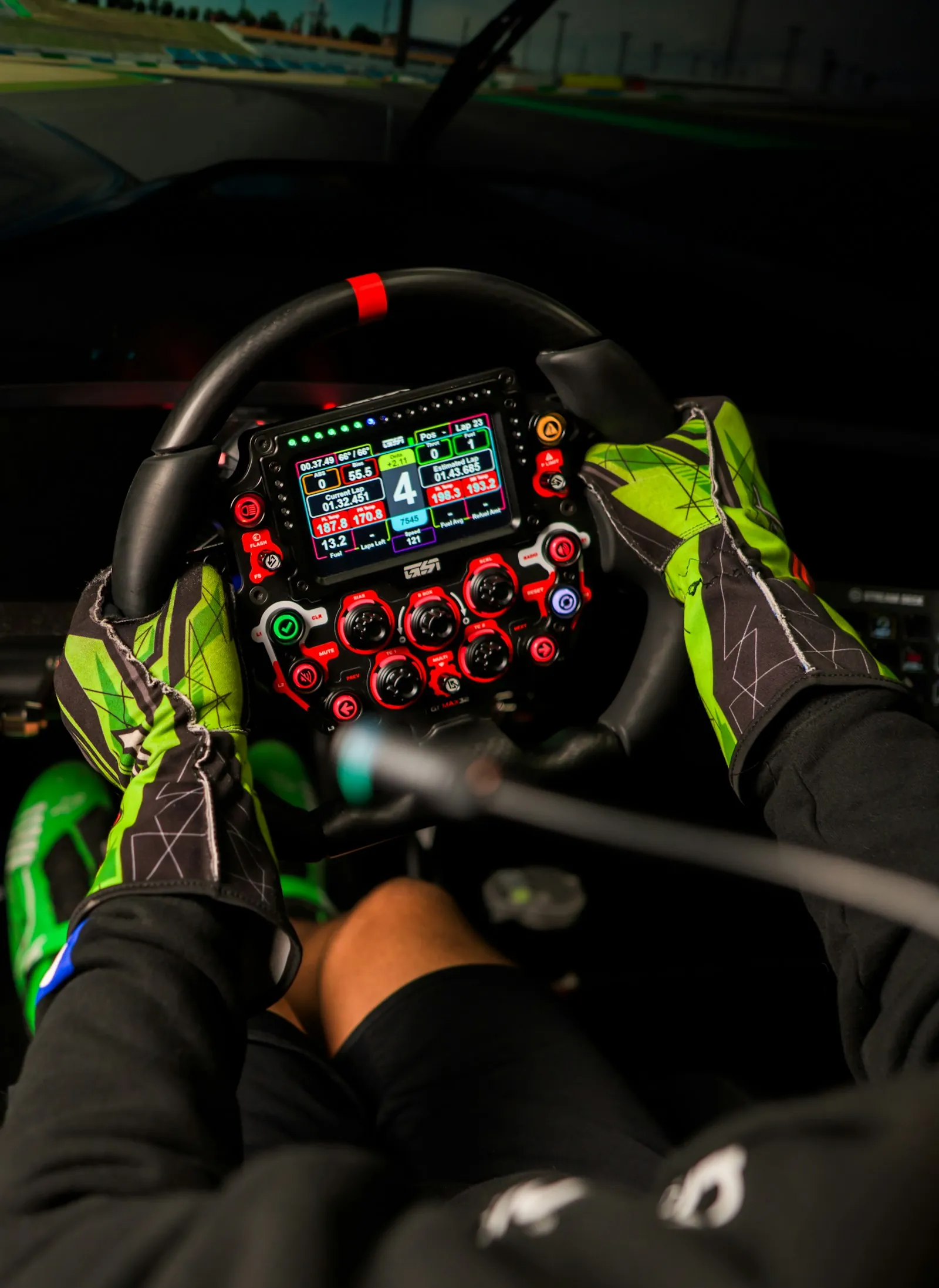Gloved hands gripping a formula style sim racing wheel with dash display