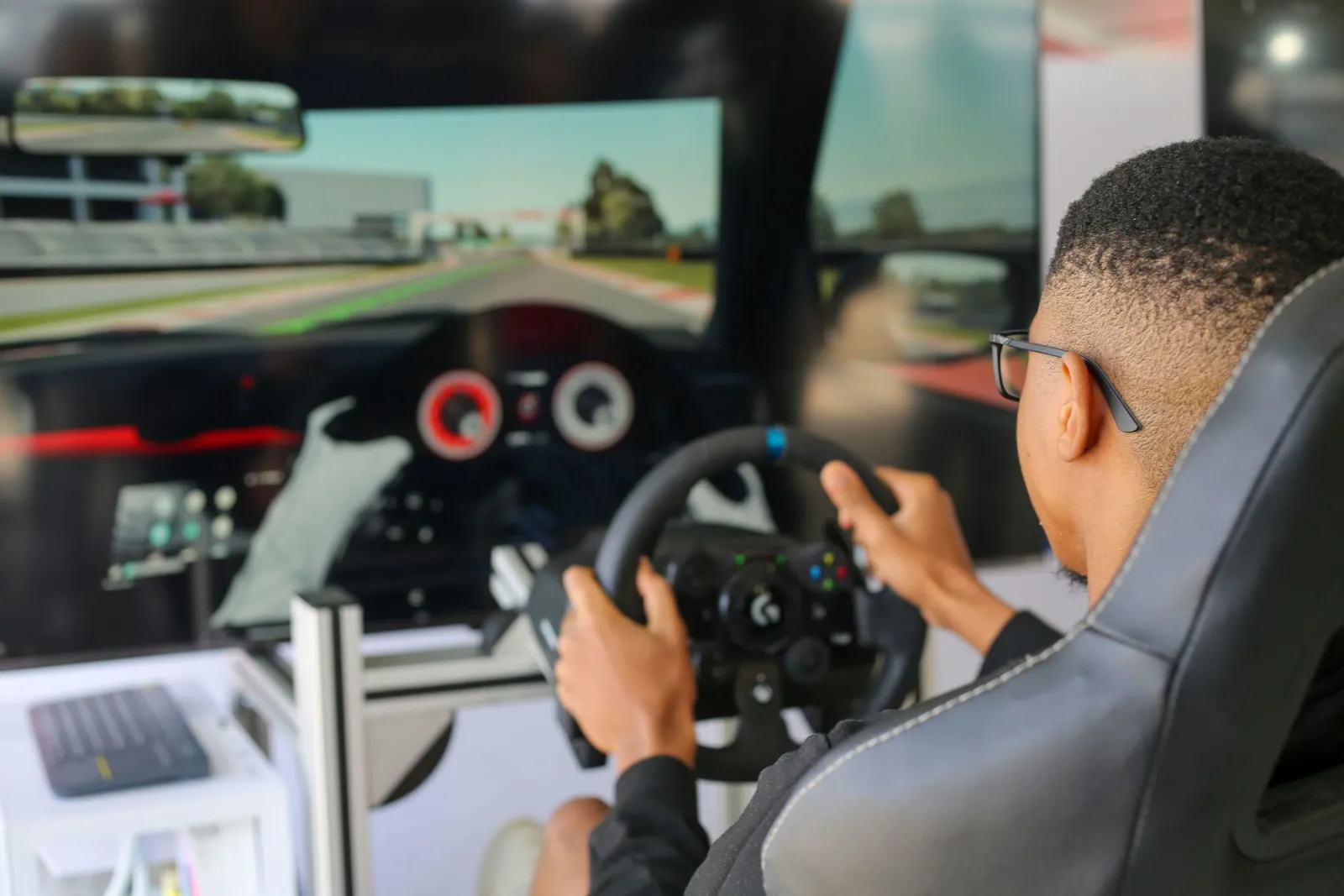 Driver turning a sim racing wheel in front of a track display